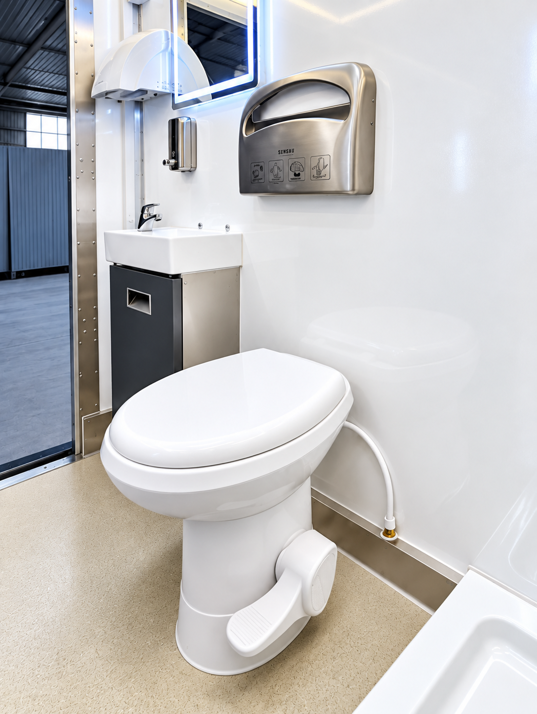 Restroom trailer interior with a toilet and yellow grab rails