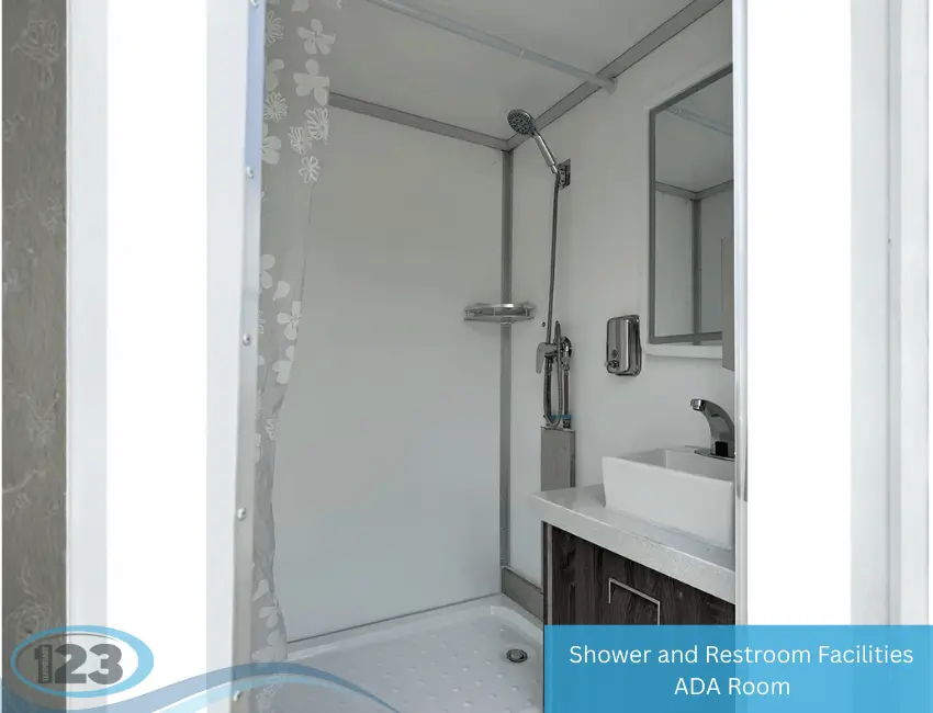 Accessible shower and restroom trailer interior with handheld shower, sink, mirror, and ADA-compliant layout