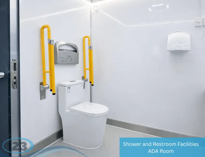 ADA-compliant restroom trailer interior with toilet, yellow grab bars, hand dryer, and paper dispenser