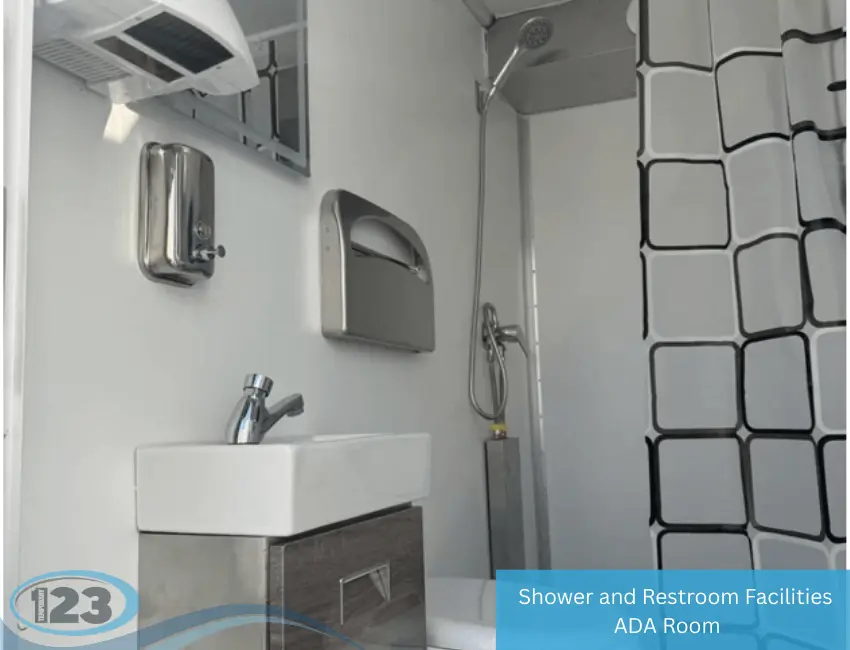 Interior of mobile shower and restroom trailer with sink, soap dispenser, paper towel holder, and handheld shower with curtain
