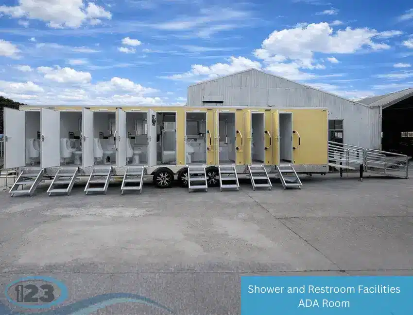 Large multi-stall shower and restroom trailer with open doors, multiple toilets, entry steps, and ADA-accessible ramp