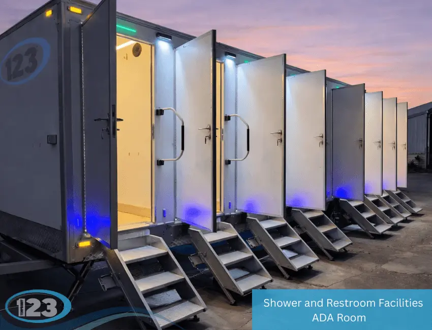 Multi-stall shower and restroom trailer with open doors, entry steps, and exterior lighting at dusk